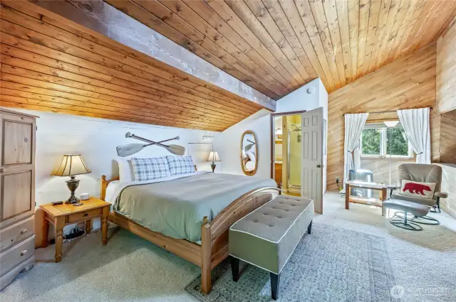 Spacious primary loft bedroom with a king-sized bed and vaulted ceilings