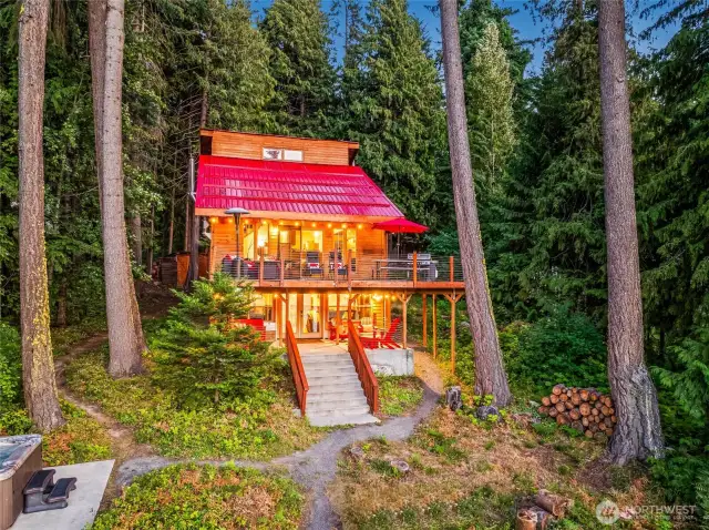 Evening glow – the backside of the home illuminated with warm interior light, multiple decks, and lake views.