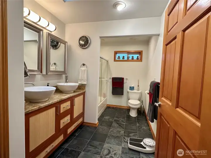 ADU full bathroom with dual sinks, custom cabinetry, and slate floors.