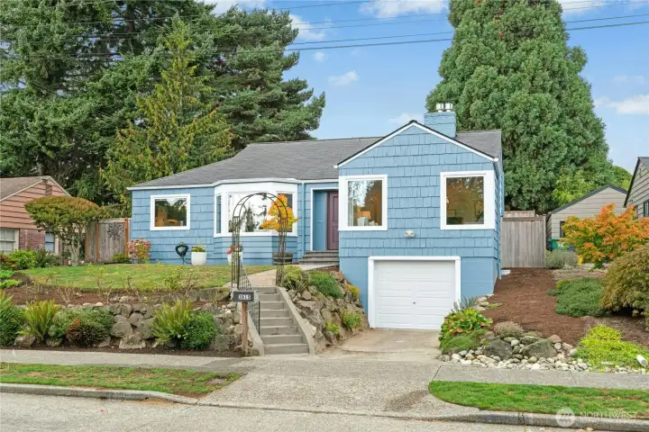 Great curb appeal framed by majestic trees in backyard.