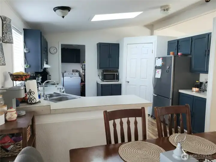 An Opposite Look at the Open Spacious Bright Kitchen with Ample Amount of Real Wood Cabinets,Huge Walk In Pantry, Counter Tops, All Appliances Stay, Cathedral Ceiling, Newer Laminate Flooring Looking into the Dining Room.