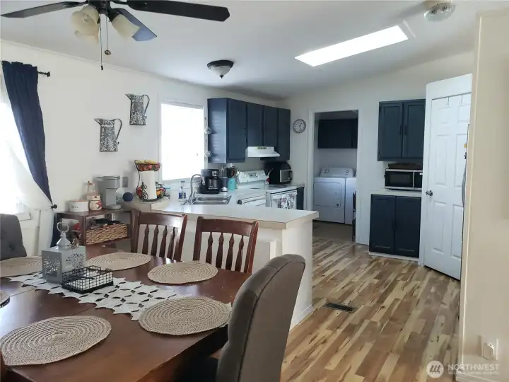 A Different View of the Open Spacious Bright Kitchen with Ample Amount of Real Wood Cabinets,Huge Walk In Pantry, Counter Tops, All Appliances Stay, Cathedral Ceiling, Newer Laminate Flooring Looking into the Dining Room.