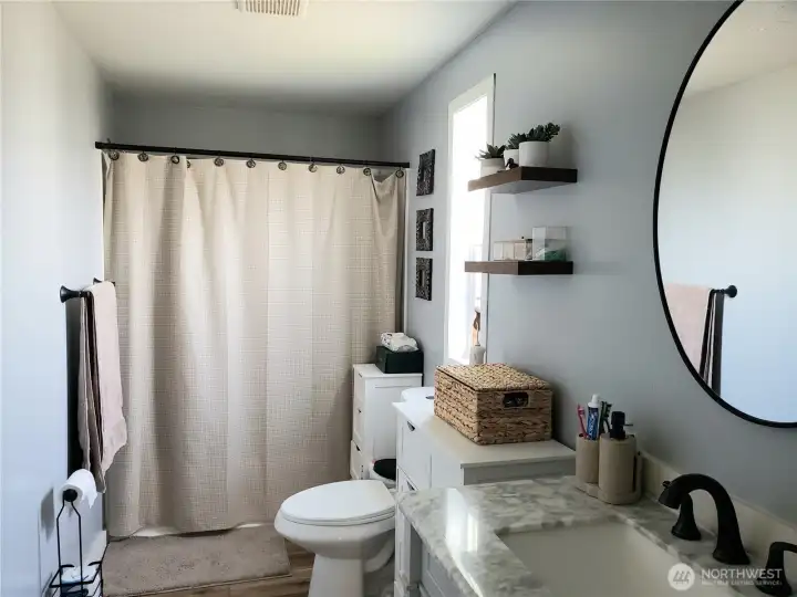 A Picture of the Large Primary Master Bath Room with Newer Paint, Trim, Sink, Toilet, Faucet, Counter Top, and Vinyl Plank Flooring.