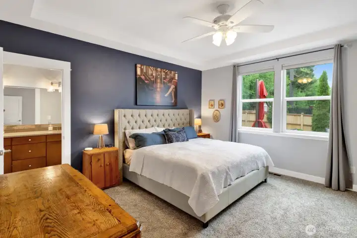 Primary suite with tray ceiling and natural light with views of the backyard.