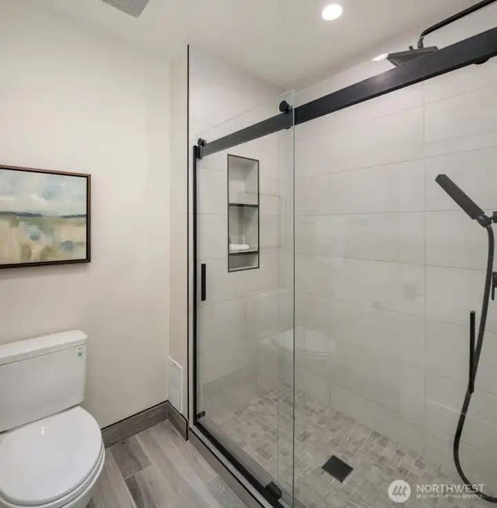 The walk-in shower features stunning glass doors.