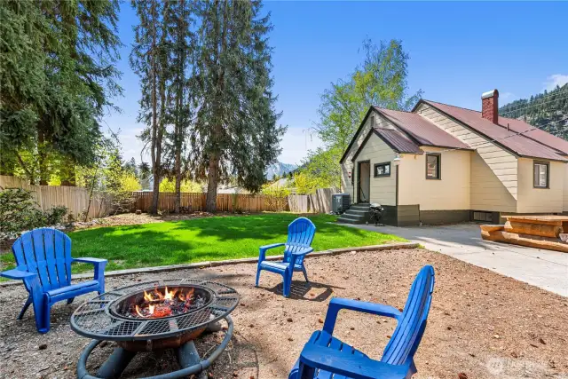 A large fenced back yard with fire pit