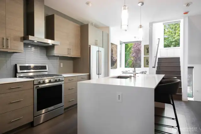 A clean, open kitchen flows seamlessly into the dining space and bright stair landing.