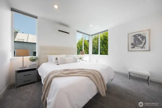Airy and serene, the primary bedroom features tree-lined views.