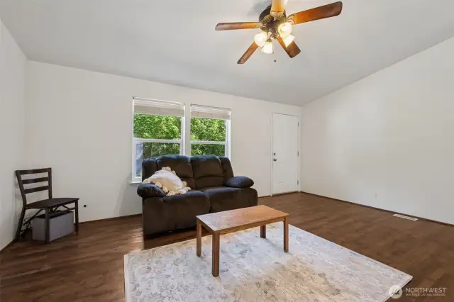 Roomy living room with attractive flooring and fan! The home has nice cross ventilation with the windows, doors and ceiling fans.