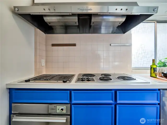 Stylish kitchen featuring bold cabinetry, stainless accents, a built-in grill, and plenty of workspace for the home chef