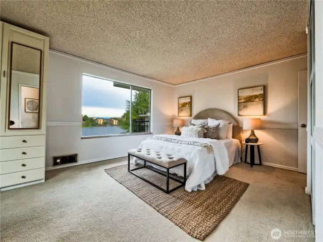 Bright bedroom with peaceful lake scenery framed by lush greenery.