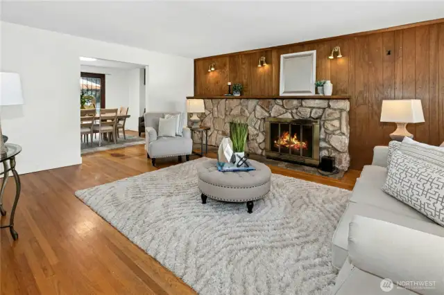 The spacious living room with wood flooring and a wood burning fireplace.