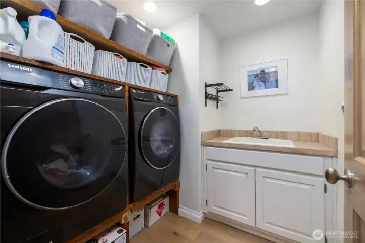 Well organized laundry room has built-in storage, engineered hardwood floor, utility sink.