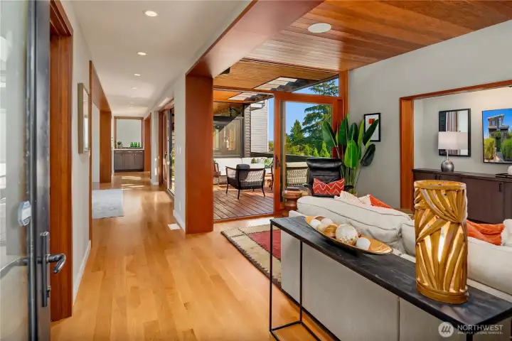 Natural light pours through wide glass doors, connecting open living spaces to a sun-soaked outdoor deck.