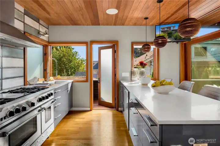 Expansive windows and sleek finishes make this kitchen a sunlit chef’s haven with direct deck access.
