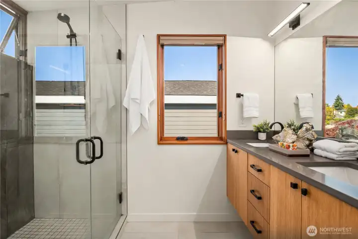 Glass and tile details define the walk-in shower, framed by natural light.