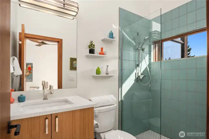 A playful pop of color elevates this stylish second bedroom bath, complete with custom tile and natural light.
