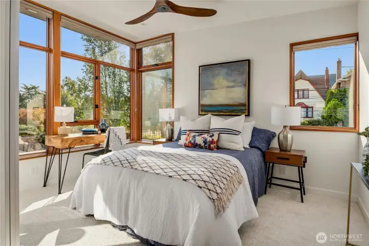 Expansive corner windows frame leafy views, filling this bedroom retreat with sunshine.