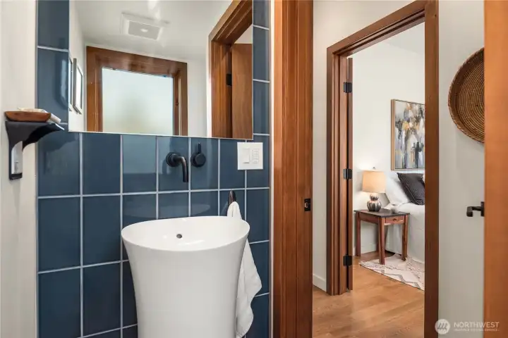 A bold powder room on the main level with striking blue tile and designer finishes makes a statement, with walk-in shower tucked just behind.