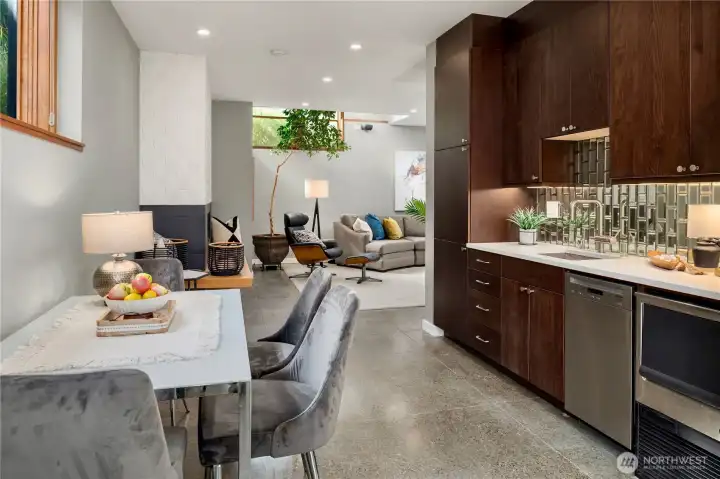 Wet bar with dishwasher, ice maker, full-size fridge, modern cabinetry and stylish backsplash enhances everyday convenience.
