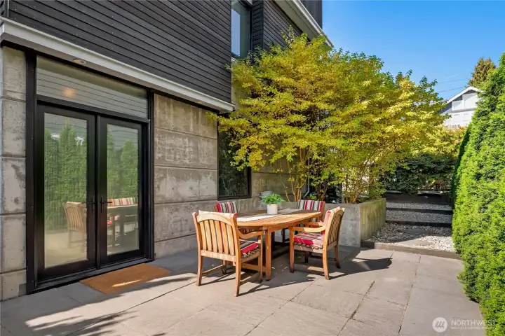 Private outdoor dining patio surrounded by lush greenery - perfect for summer evenings or crisp fall mornings.