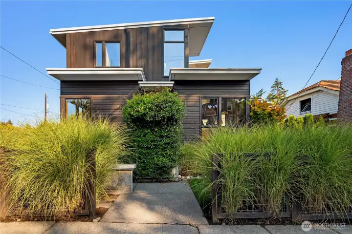 A lush, private entry framed by grasses and greenery sets a welcoming tone.