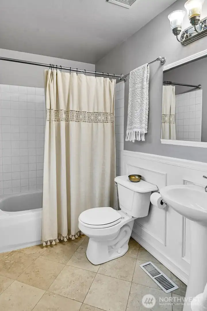 And here's the full primary bath, which includes a pedestal sink and charming wainscoting detail.