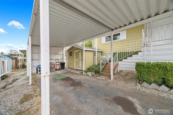 Covered parking area with storage shed.