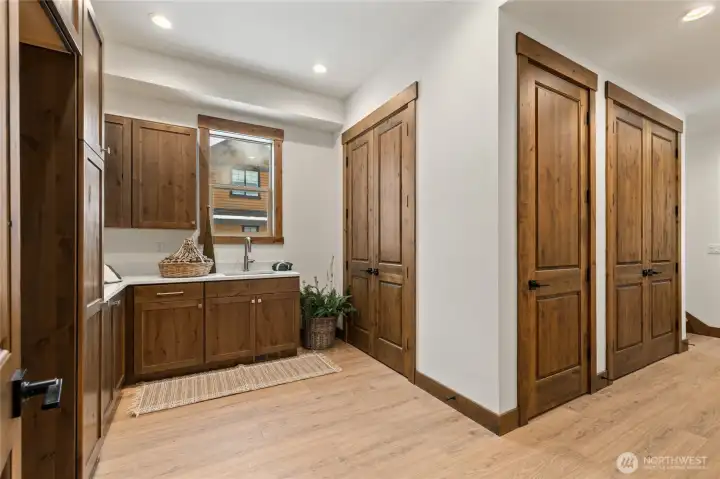 Large laundry room with built in cabinetry and convenient sink. Back stair case leads to bonus room and hallway to garage.