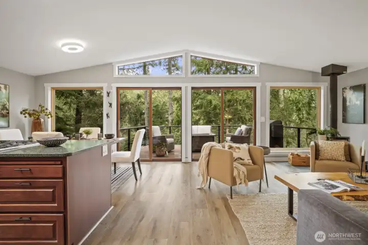 The main living area features walls of windows that bring the outdoors in, with sliding doors leading to the expansive upper deck.