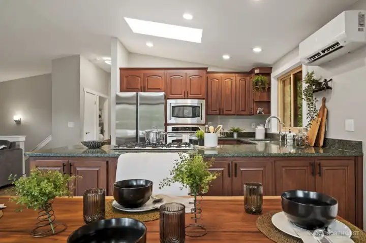 Beautifully updated kitchen showcasing rich cherry cabinetry, slab granite countertops, and tile flooring.