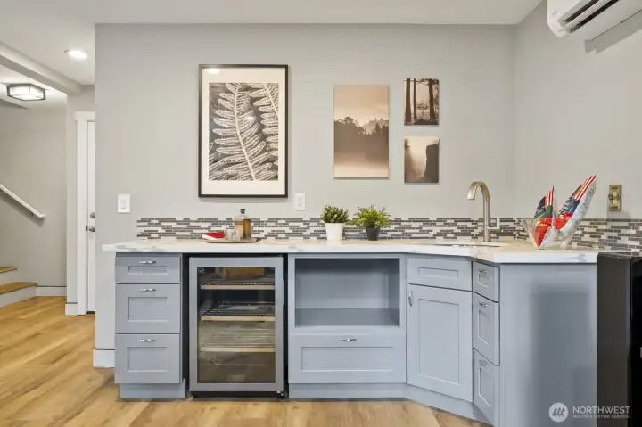 Lower level equipped with a wet bar/second kitchen featuring a fridge, sink, quartz countertops, and plenty of cabinet storage.