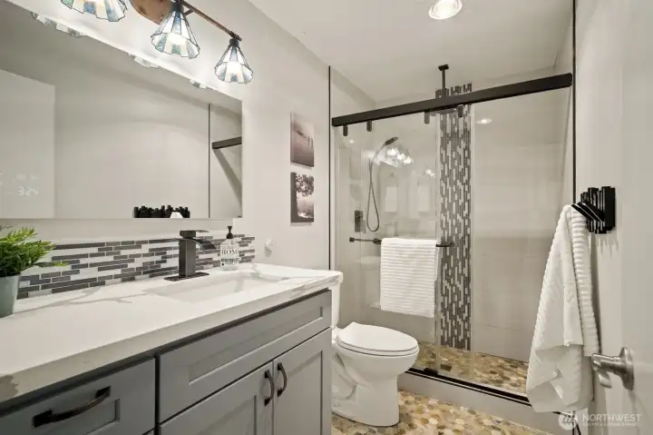 Stylish remodeled lower 3/4 bath with heated floors, custom tile, smart mirror, and hands-free flush toilet.