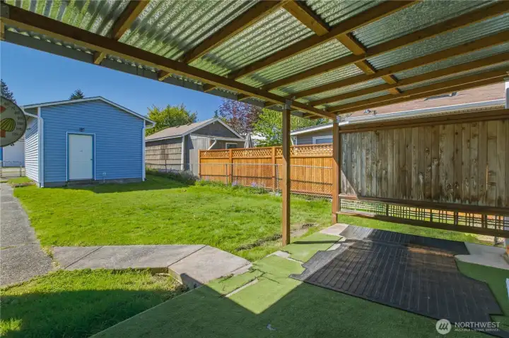Covered patio in the backyard with additional storage in the unattached garage.