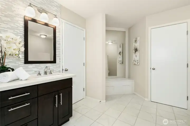 Primary bath with dual vanity and large mirror with seating area