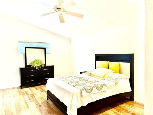 Large master bedroom with hardwood floors, vaulted ceiling, and ceiling fan.
