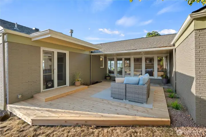 Two sets of French doors open onto a brand-new deck, seamlessly extending the living room and kitchen spaces outdoors.