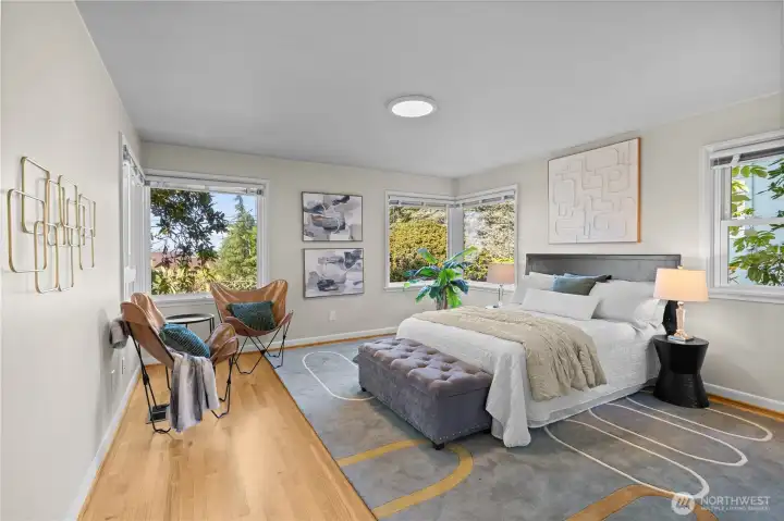 This spacious bedroom on the main floor is bathed in natural sunlight thanks to large windows and a neutral color palette.