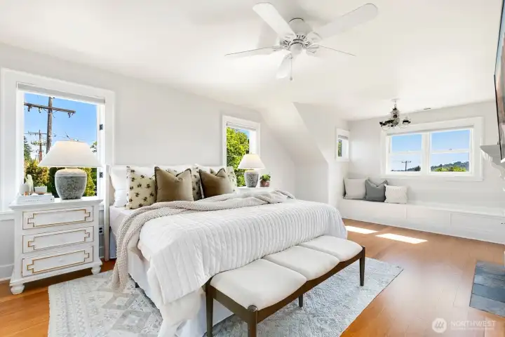 Head upstairs to one of two bedrooms - primary first! The light in here and space - perfection. This is a king sized bed with large furniture. and there's still so much space. Note the built-ins under the windows - storage all around!