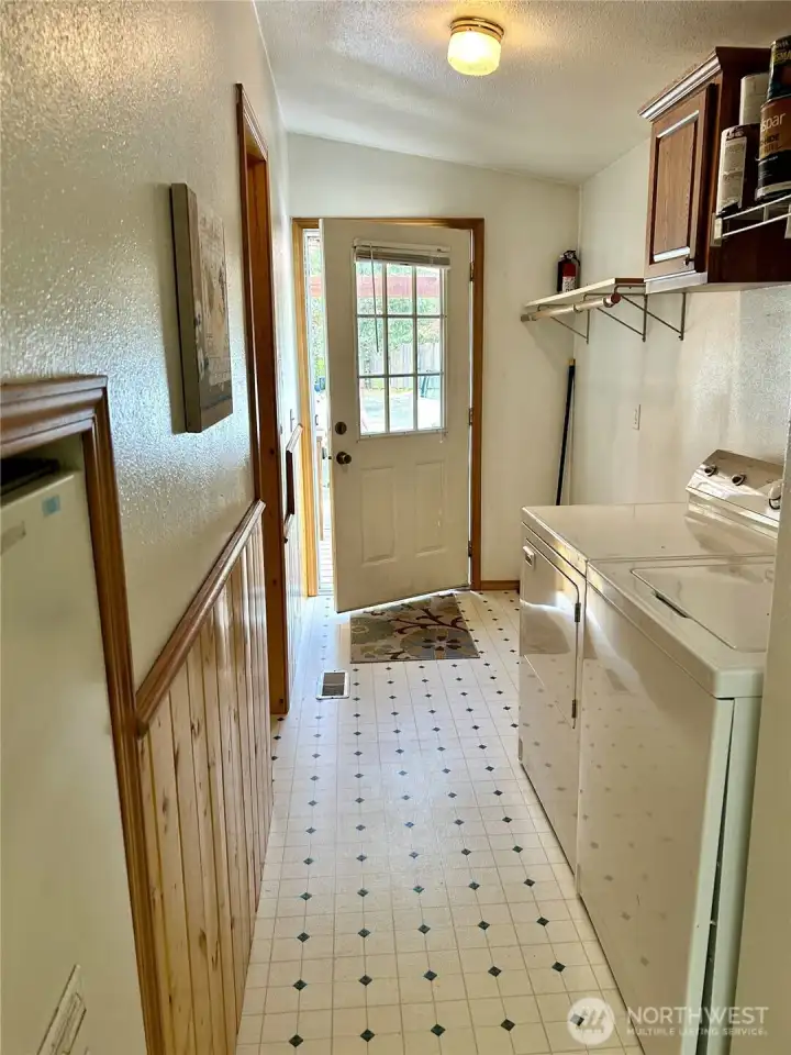 View of laundry room. Washer and Dryer included.  Storage over washer and dryer plus hanging bar. Door leads out to covered deck area.