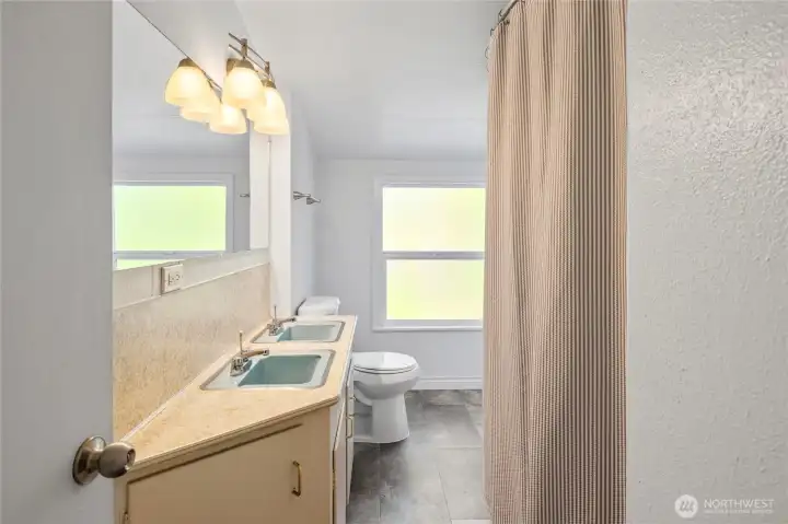 Full size guest bathroom located upstairs between 3rd and 4th bedrooms, new paint and window and new tub surround. Love the original blue sinks too.