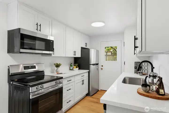 Note the side door at the end of the kitchen. So convenient for loading groceries and other items into house, letting doggies out and most importantly flowing out to relax on the outdoor patio and firing up the BBQ!