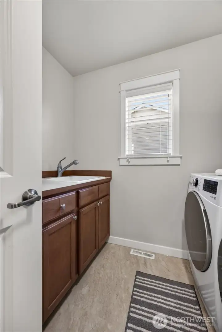 Upstairs utility room with cabinets, sink and shelving.