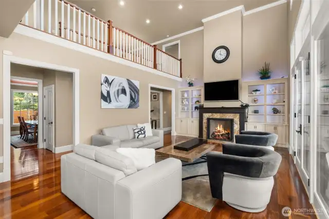 Perfectly designed for entertaining, the open-floor plan offers ample room for guests, while the floor-to-ceiling windows provide breathtaking views that seem to go on forever. A second staircase gracefully leads to additional bedrooms and the state-of-the-art theater room, offering both privacy and access. Built-in shelving and a gas fireplace enhance the room's cozy yet elegant atmosphere, while the mantel introduces easy elegance. The custom cabinetry provides a special space to display treasured art pieces. As you take it all in, let the peaceful energy of this home wash over you, offering both serenity and sophistication.