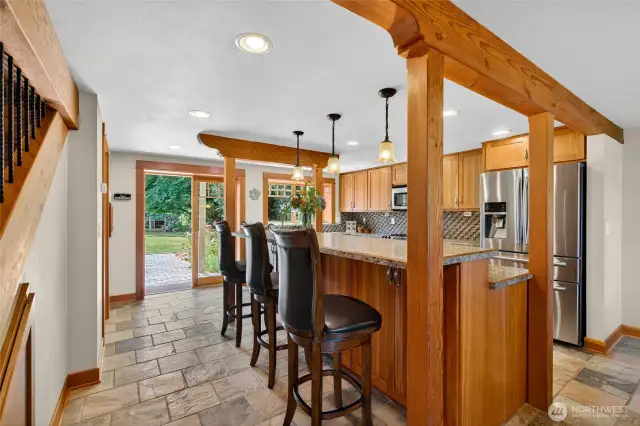 The first-floor kitchen highlights the warmth of Douglas fir wood and cherry wood cabinets, offering a beautiful view of the backyard patio and garden.