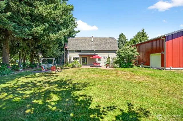 Large patio area with lawn area for a campfire space. Side roll up door for entry into the shop.