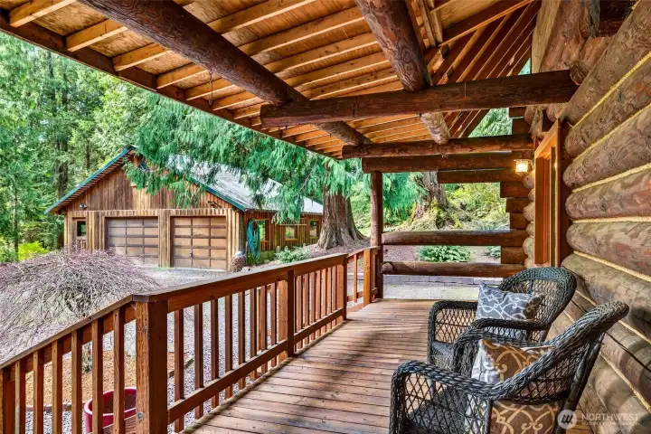 From the rear deck, a detached garage and sweeping old-growth trees define the backdrop — exposed log beam ceiling overhead and generous deck space make this an exceptional outdoor retreat for relaxing or entertaining in total privacy.