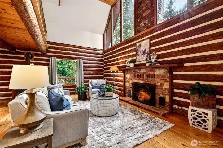Rich log wall construction, a vaulted ceiling with exposed timber beams, and a classic brick hearth create a living room experience that feels both grand and deeply intimate — this is the kind of space that makes you want to stay in.