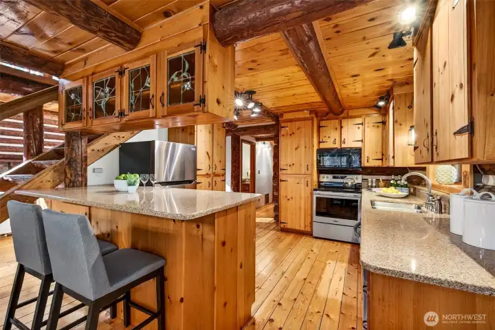 The updated kitchen delivers serious functionality wrapped in rustic elegance — quartz counters, stainless appliances, a generous bar seating, and leaded glass upper cabinetry make this a workspace that is as beautiful as it is practical.