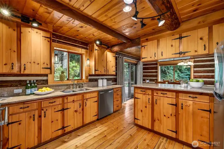 Abundant knotty pine cabinetry, dual prep and sink areas, stainless dishwasher, and garden-framed windows create a kitchen designed for those who love to cook and gather — every detail reflects the craftsmanship that defines this one-of-a-kind home.